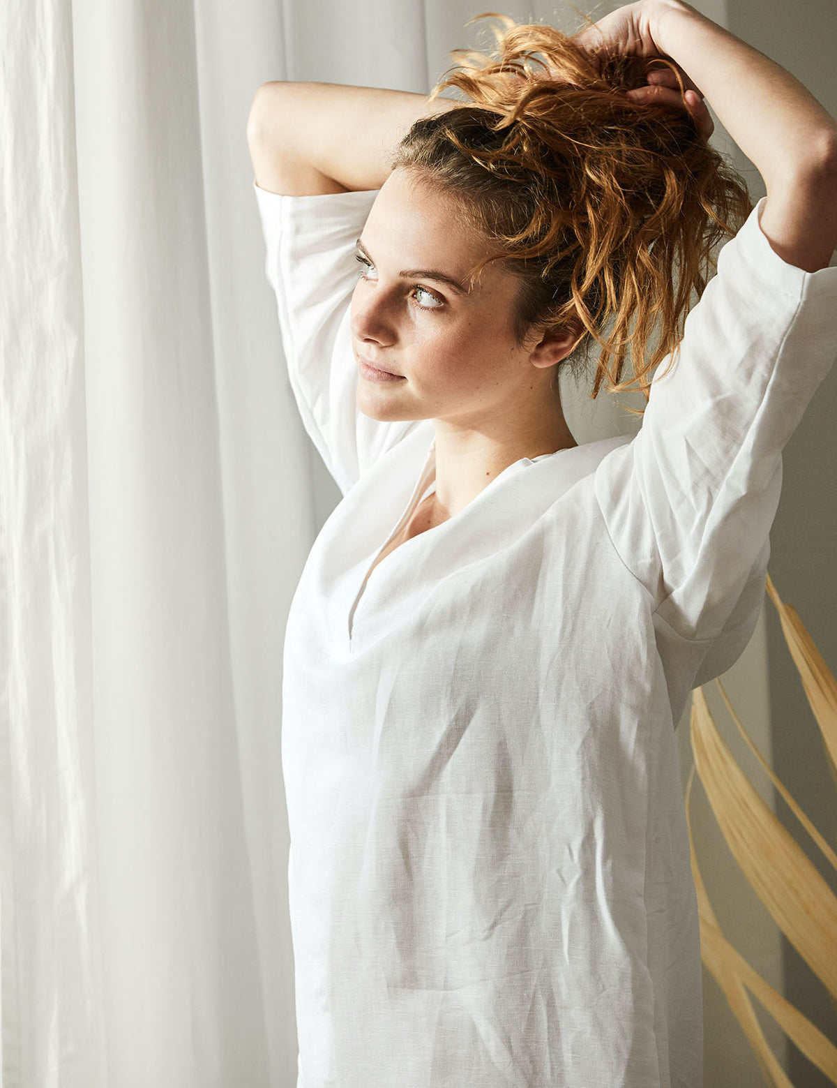 Frau mit Halbleinen Homewear blickt aus Fenster 